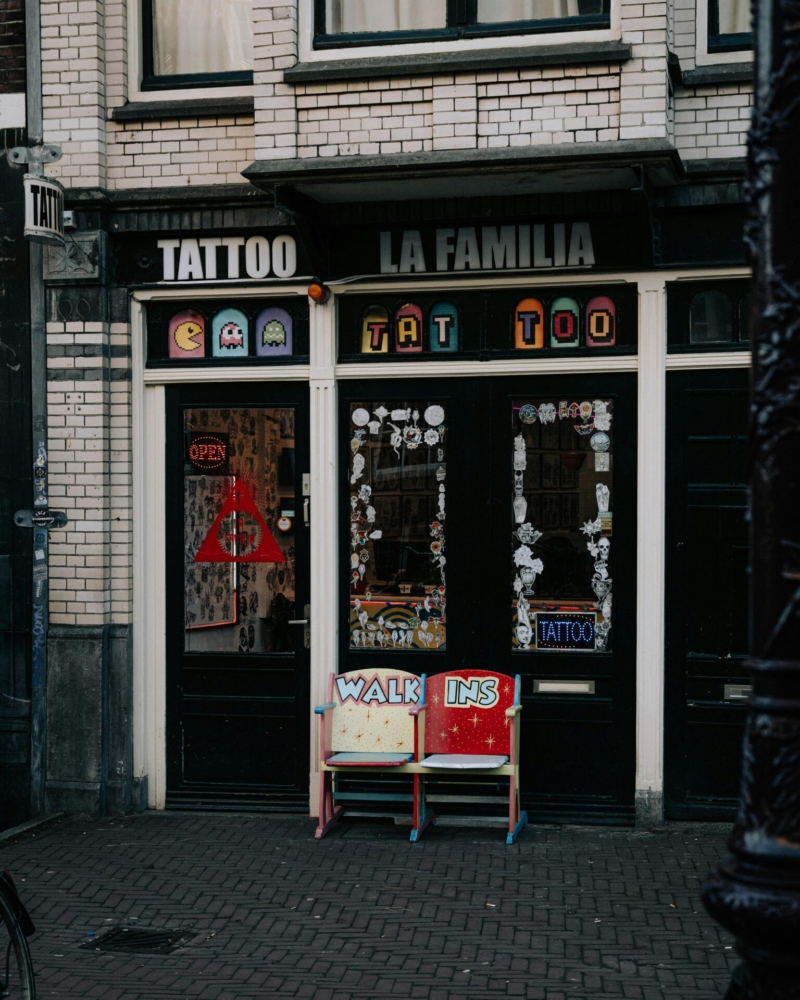 Street view of a vibrant tattoo shopfront in Amsterdam. Ideal for urban exploration and cultural themes.
